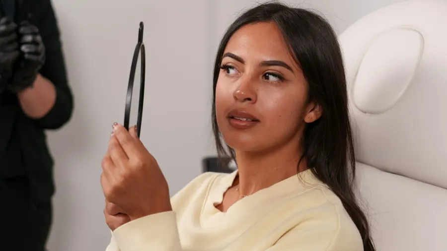 Patiente se regardant dans un miroir lors d'une consultation esthétique