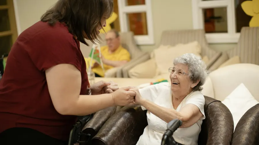 Soignante aidant une dame âgée à se lever avec son déambulateur