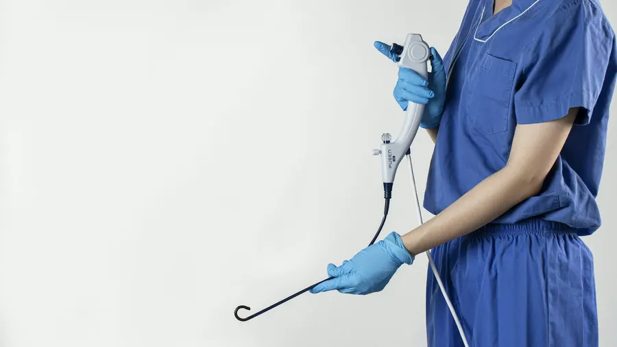 Gastro-entérologue en tenue de soins tenant un endoscope