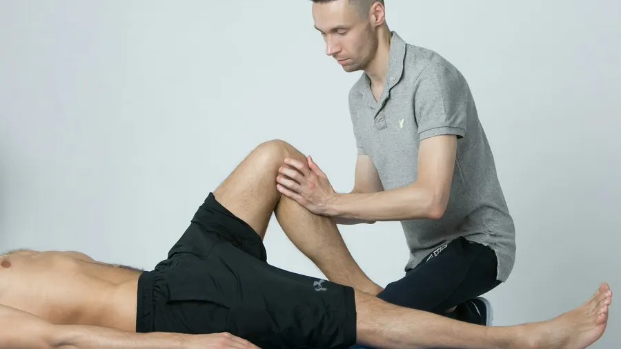 Praticien examinant le genou d'un sportif allongé