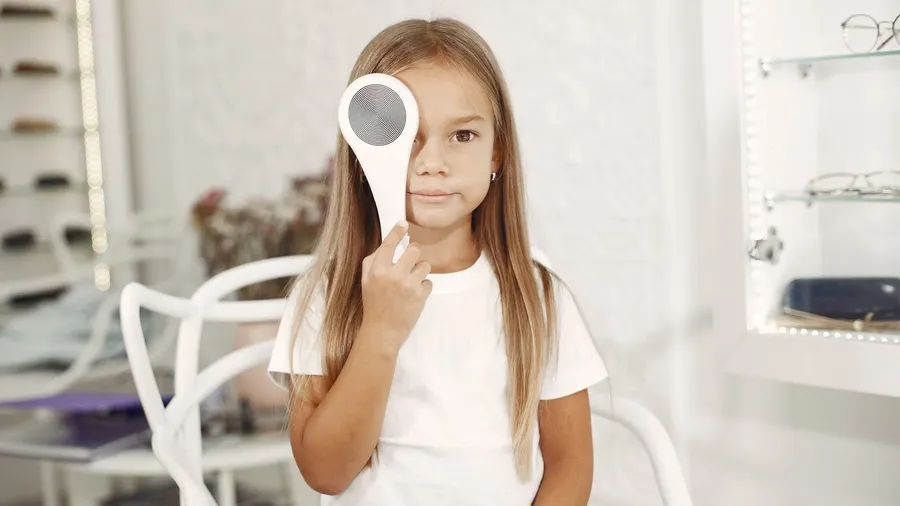 Fillette cachant un œil avec un occluteur pendant un bilan de la vue